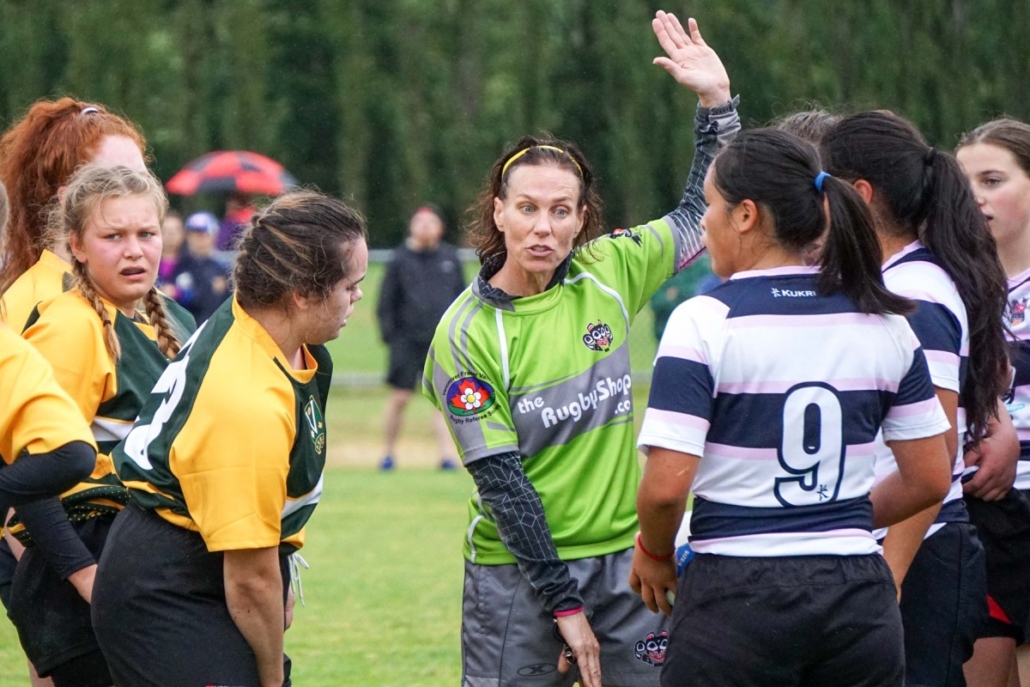 A referee talks to two players on the pitch