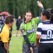 A referee talks to two players on the pitch