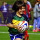 A young girl smiling as she runs with a rugby ball