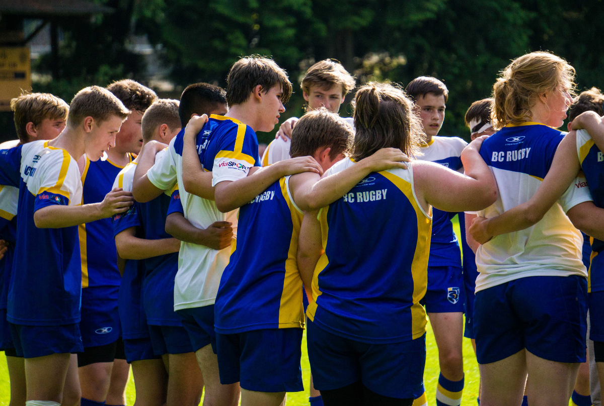 A group of male rugby players stand in a huddle