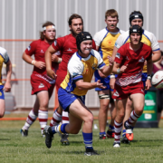A rugby player throws the ball as opposing players chase him
