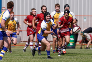 A rugby player throws the ball as opposing players chase him