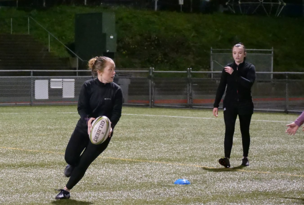 A female rugby player runs with the ball during training