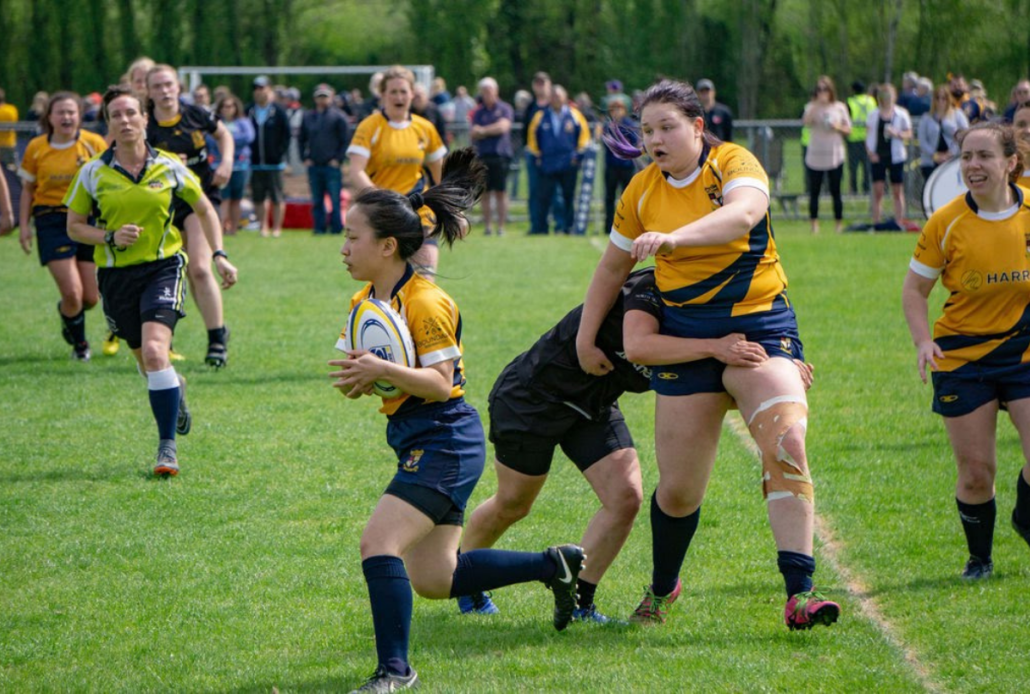 A female Rugby player runs with the ball during a championship match