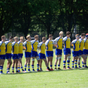 A team of rugby players dressed in gold shirts and blue shorts line up
