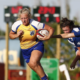 A female BC Bears rugby player carries the ball away from opponents