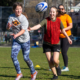 Young girls throw rugby balls to each other during a tryout session