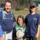 Two women and a young girl holding a Rugby ball pose for a photo