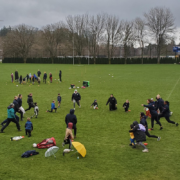 A group of rugby coaches teach a session for Mini Rugby athletes on a field