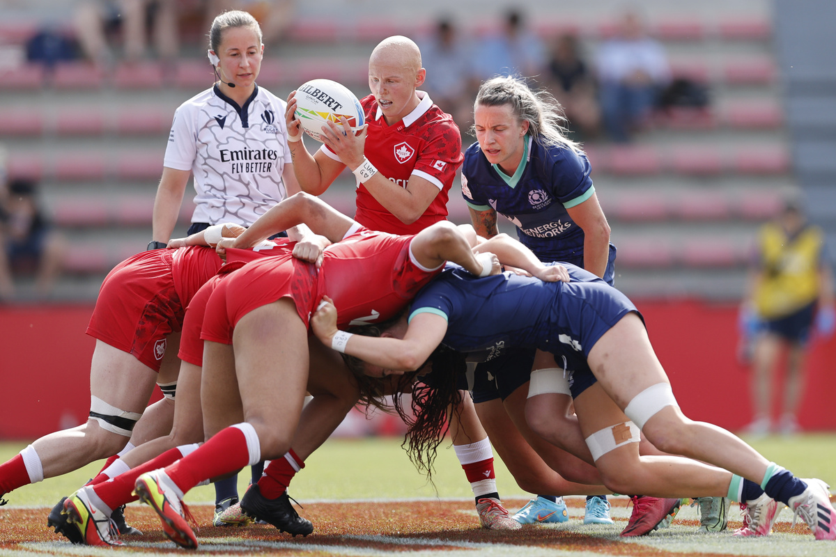 Canada and Scotland Women's Rugby Sevens teams contest a scrum in the middle of the pitch