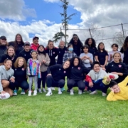 A group of Rugby Canada female athletes pose with school children on a field