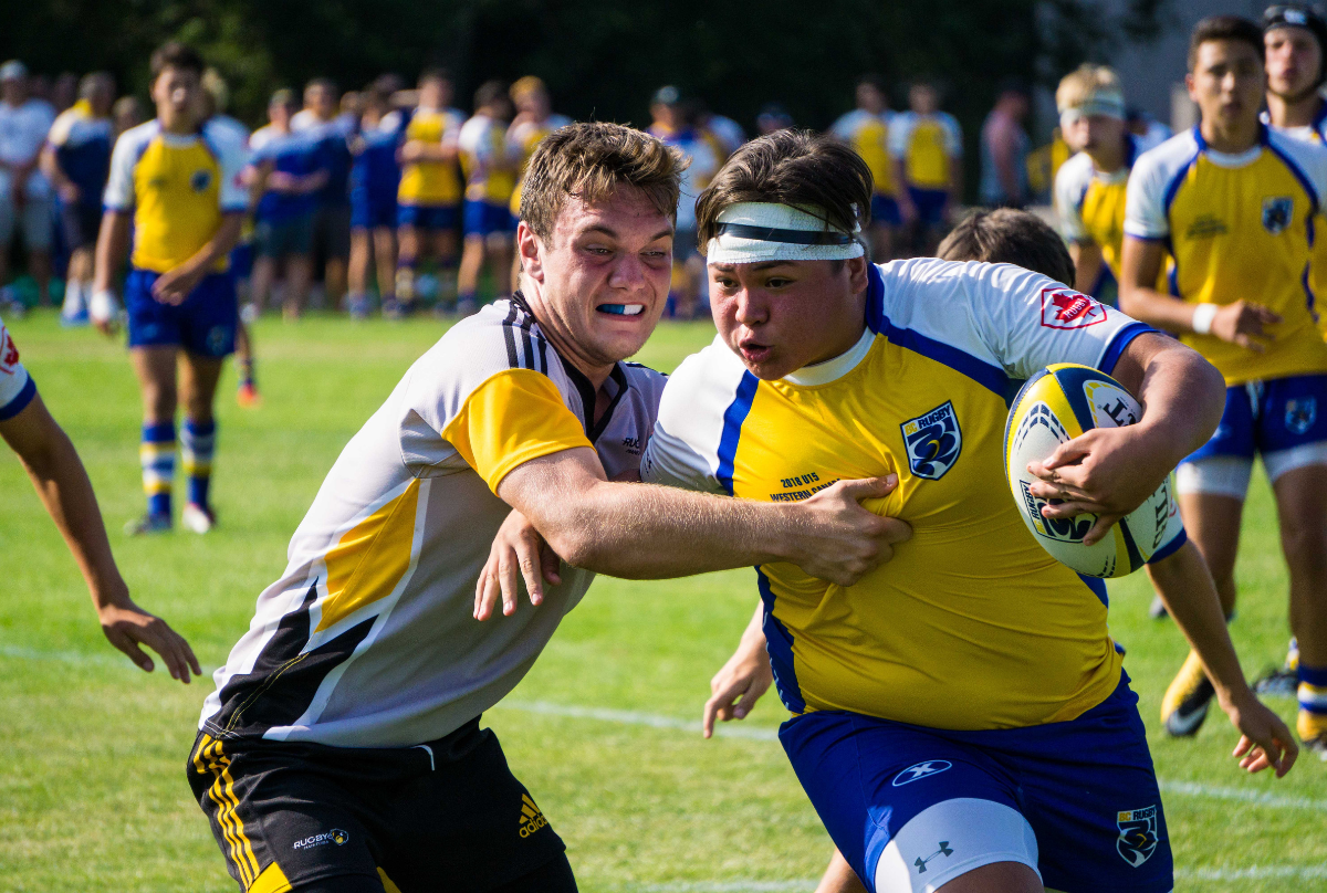 A BC Rugby player carrying the ball powers past an opposing player