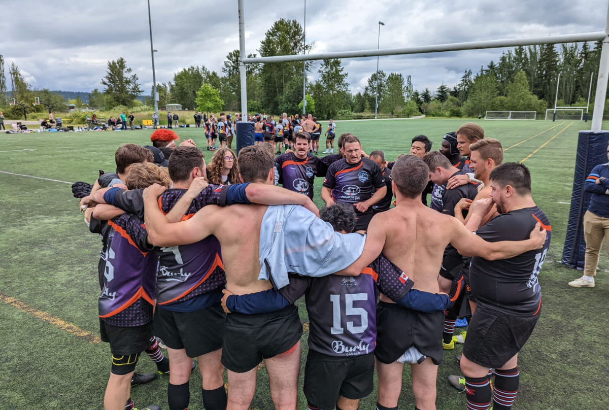 The Vancouver Rogues Rugby team huddles around their coach giving a team talk