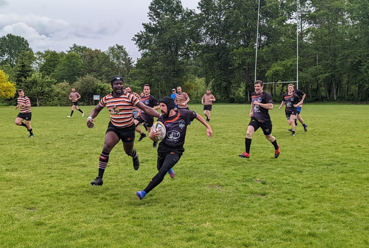 A Rugby player chases an opposing player with the ball as team-mates run in the background