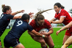 A Rugby Canada Women's Player carries the ball into two tackles during a match against the USA