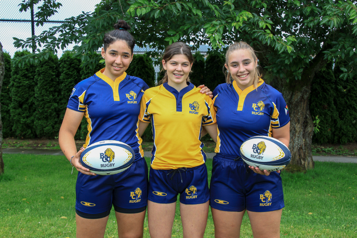 A group of three female players model the new navy and gold BC BEars kits
