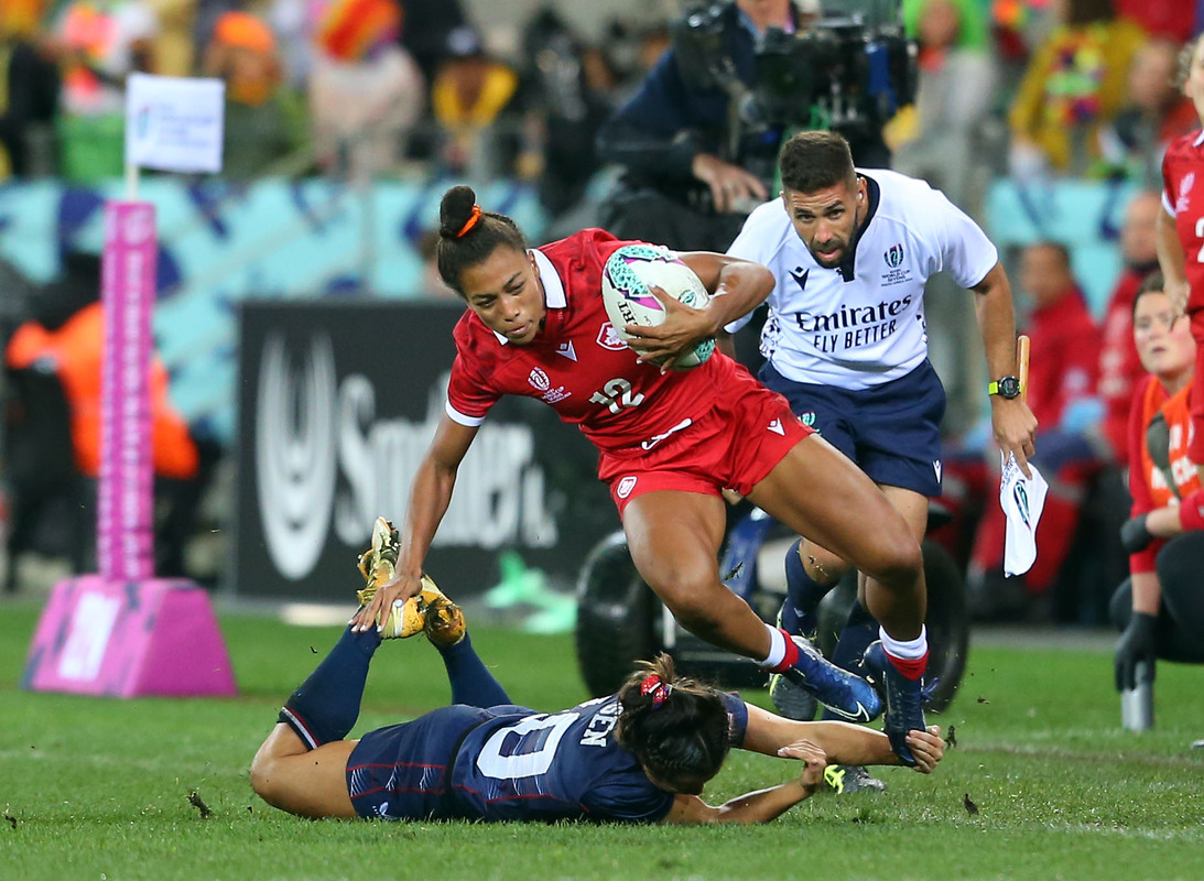 A Canada player runs past a Fiji player in the Rugby World Cup 7s Women's match