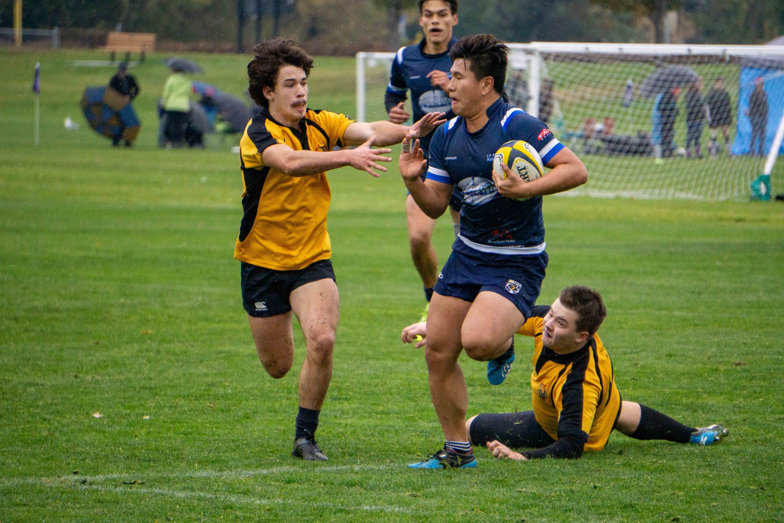 A male Rugby player runs with the ball and evades the opponent