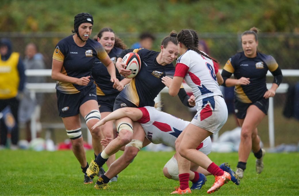 A UBC Thunderbirds player rides a tackle from a Acadia player during the consolation final at the 2022 U SPORTS Championship