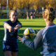A girl throws a rugby ball to her coach during a skills session