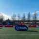 A generic shot of a blue BC Rugby banner that says Join the Game in front of a red inflatable Rugby pitch