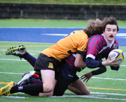 A United RFC Boys player offloads the ball as he is tackled